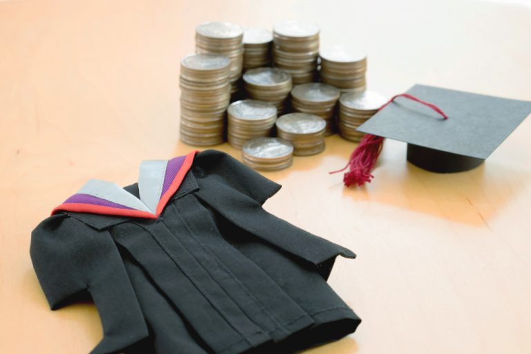 a graduation dress, cap and stacks of coins representing education
